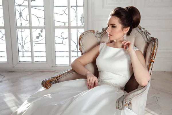 Ritratto di bella sposa bruna con acconciatura elegante e trucco indossando lungo abito da sposa di lusso — Foto Stock