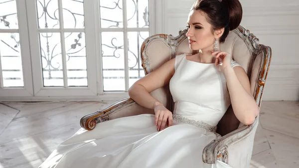 Retrato de bela noiva morena com penteado elegante e maquiagem vestindo vestido de noiva de luxo longo — Fotografia de Stock