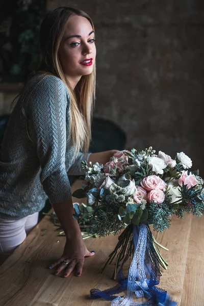 Florista en el trabajo: mujer rubia bastante joven sostiene ramo moderno de moda de diferentes flores — Foto de Stock