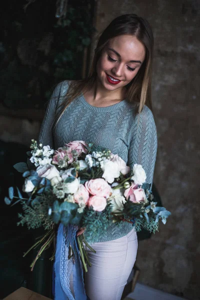 Florista en el trabajo: mujer rubia bastante joven sostiene ramo moderno de moda de diferentes flores — Foto de Stock