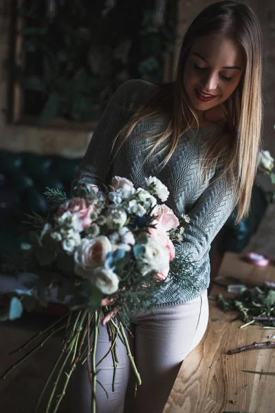 Florista en el trabajo: mujer rubia bastante joven sostiene ramo moderno de moda de diferentes flores — Foto de Stock