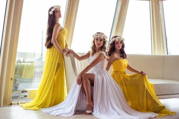 Όμορφη νύφη και δύο bridesmaids σε κίτρινο παρόμοια φορέματα μαζί σε ένα εστιατόριο στη θάλασσα — Φωτογραφία Αρχείου