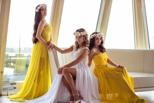 Hermosa novia y dos damas de honor en vestidos amarillos similares juntos en un restaurante de mar —  Fotos de Stock