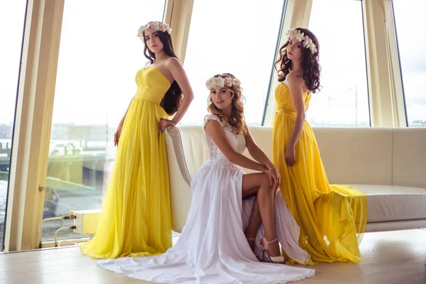 Красива наречена і дві подружки нареченої в жовтих подібних сукнях разом в морському ресторані — стокове фото