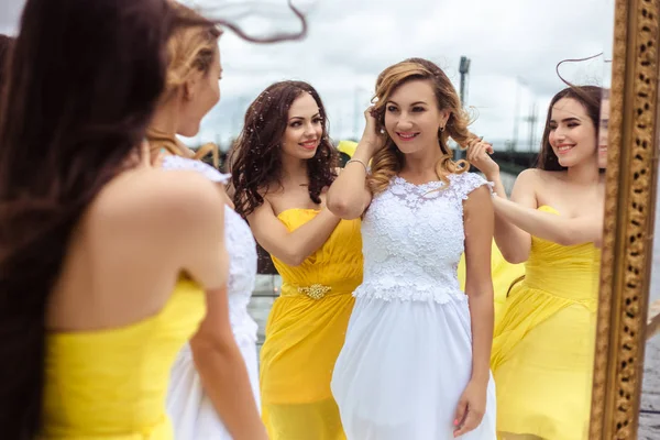 Noiva bonita e duas damas de honra em vestidos semelhantes amarelos em conjunto em um terraço de verão um restaurante do mar — Fotografia de Stock