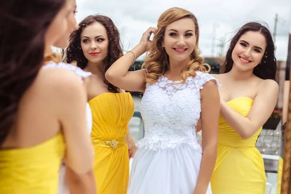 Noiva bonita e duas damas de honra em vestidos semelhantes amarelos em conjunto em um terraço de verão um restaurante do mar — Fotografia de Stock