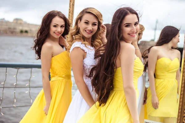 Жених и две невесты в желтых похожих платьях вместе на летней террасе морского ресторана — стоковое фото