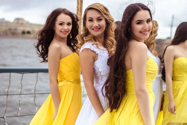 Красива наречена і дві подружки нареченої в жовтих подібних сукнях разом на літній терасі морський ресторан — стокове фото