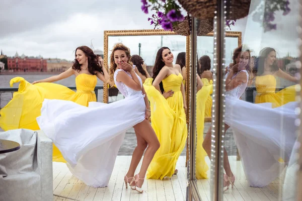 아름 다운 신부와 노란색 비슷한 드레스는 여름에 함께 있는 두 신부 들러리 테라스 바다 식당 — 스톡 사진