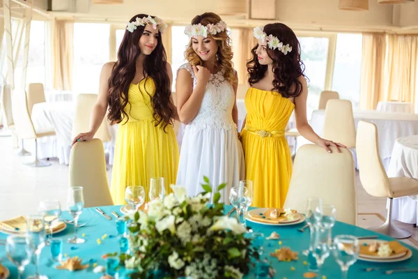 Noiva bonita e duas damas de honra em vestidos semelhantes amarelos juntos em um restaurante do mar — Fotografia de Stock