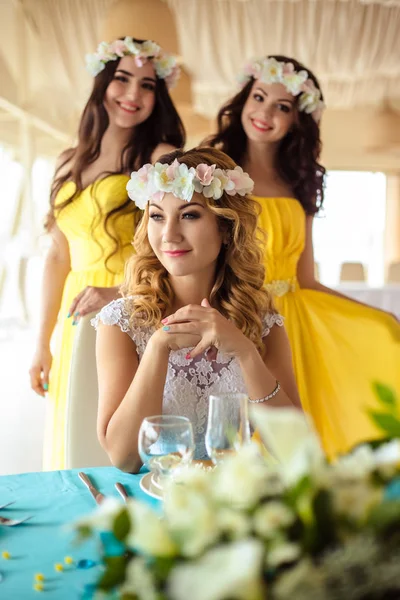 Schöne Braut und zwei Brautjungfern in gelben ähnlichen Kleidern zusammen in einem Meeres-Restaurant — Stockfoto