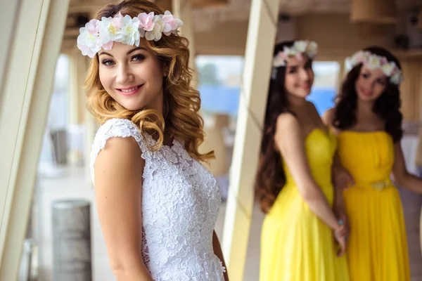 Noiva bonita e duas damas de honra em vestidos semelhantes amarelos juntos em um restaurante do mar — Fotografia de Stock