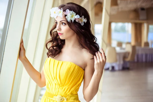 Hermosa joven con el pelo largo en un día de verano. dama de honor en vestido amarillo en un restaurante de mar — Foto de Stock