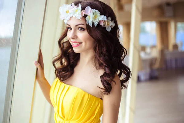 Hermosa joven con el pelo largo en un día de verano. dama de honor en vestido amarillo en un restaurante de mar —  Fotos de Stock