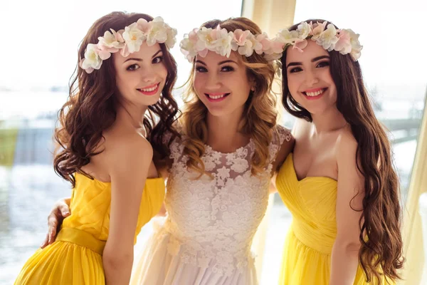 Noiva bonita e duas damas de honra em vestidos semelhantes amarelos juntos em um restaurante do mar — Fotografia de Stock