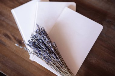 Close-up photo of light pink scheduler notebook on a wooden table with lavender. Flat lay composition.