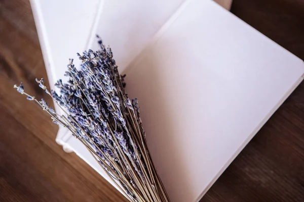Close-up photo of light pink scheduler notebook on a wooden table with lavender. Flat lay composition.