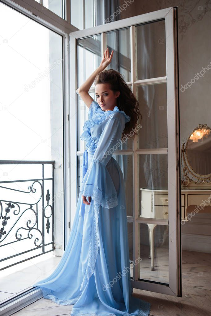 Beautiful bride young woman in a blue long peignoir in a wedding morning
