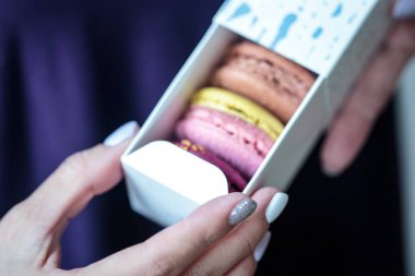 Kutusu içinde macaroons ile altın bir yay ile mevcut. Kadın bir kutu bisküvi ile tutar.