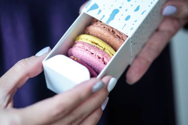 Kutusu içinde macaroons ile altın bir yay ile mevcut. Kadın bir kutu bisküvi ile tutar.