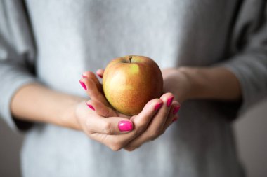 Mükemmel pembe manikürlü kadın elleri bir elma tutar, konsept fotoğraf.