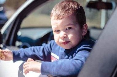 Küçük çocuk arabanın camından dışarı bakıyor.