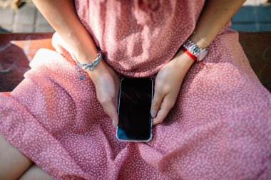 Bankta oturan cep telefonuna bakan tanınmayan bir kadın. İyi ya da kötü haberleri bekliyor..