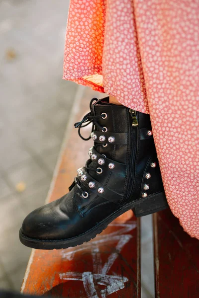 Side view of Woman's Black Leather Ankle Boots With Straps, Metal Studs And Zipper, Shot in a bench with graffiti on the street. — Stock Photo, Image