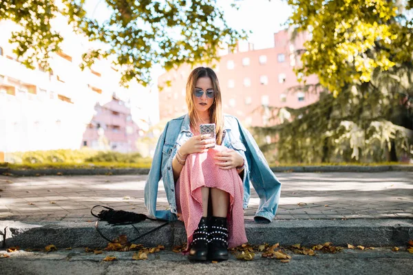 Pensive young woman with sunglasses sitting on the sidewalk look