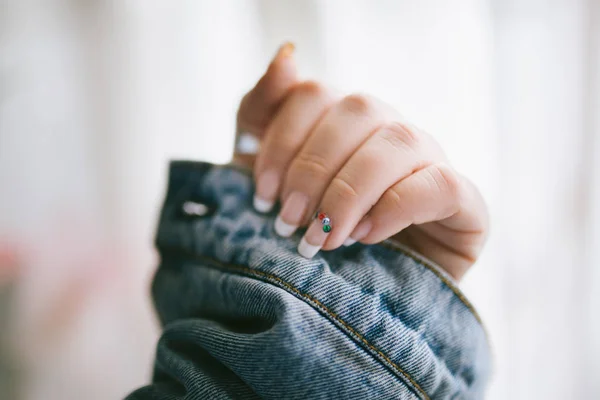 Elegancka i długotrwała kobieta francuski manicure z kolorowymi koralikami i dżinsową kurtką. Dama z francuskim manicure. Piękne żeńskie paznokcie. Pojęcie kobiecości i piękna — Zdjęcie stockowe