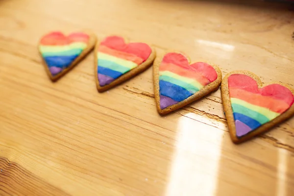 LGTB corazones galletas en una mesa de madera. Galleta de corazón arco iris. Corazón lgbt + signo de rayas de color arco iris. Concepto simbólico de amor libre . — Foto de Stock