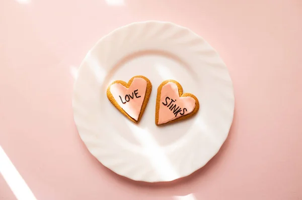 Dos galletas de jengibre corazón decoradas con fondant rosa con el mensaje de amor apesta. concepto de angustia . — Foto de Stock