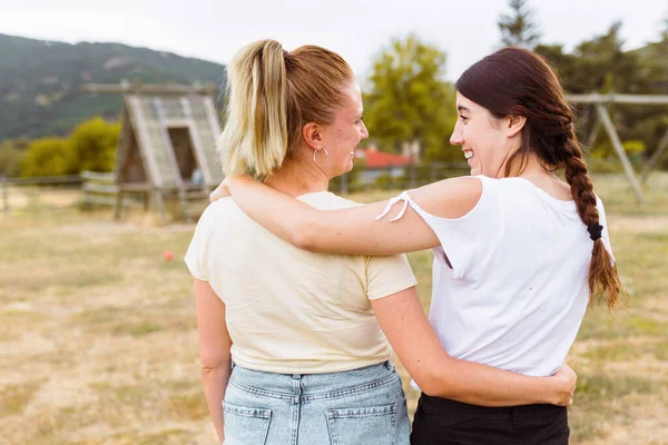 Vista trasera de dos amigos sonriendo y abrazándose en el campo. Mejor amigo amor y concepto de amistad . — Foto de Stock