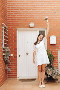 Mutlu ve gülümseyen gelin düğün buketiyle kolunu kaldırıyor.