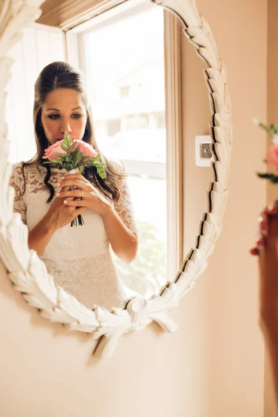 เจ้าสาวก่อนงานแต่งงาน มองดูกลิ่นช่อดอกกุหลาบ ในกระจกอย่างกังวล วันสําคัญ การแต่งงานและการแต่งงาน . — ภาพถ่ายสต็อก