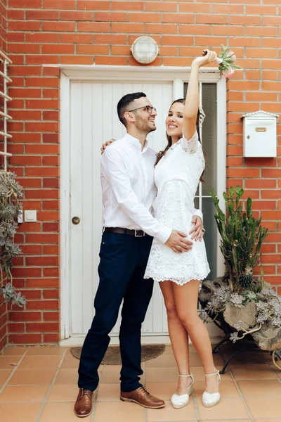 Happy groom and bride hugging and raising her arm with her weddi — Stock Photo, Image