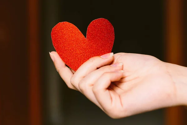 ผู้หญิงสาวที่มีกระดาษแข็งรูปหัวใจแวววาวสีแดงบนมือ ผู้หญิงที่ถือหัวใจกระดาษแข็งสําหรับวันวาเลนไทน์ ความรักและแนวคิดวาเลนไทน์ . — ภาพถ่ายสต็อก