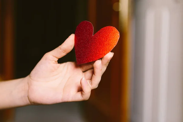 Elinde kırmızı, pırıl pırıl bir kalp olan genç bir kadın. Sevgililer Günü için karton kalp taşıyan bir kız. Aşk ve Sevgililer Günü konsepti. — Stok fotoğraf