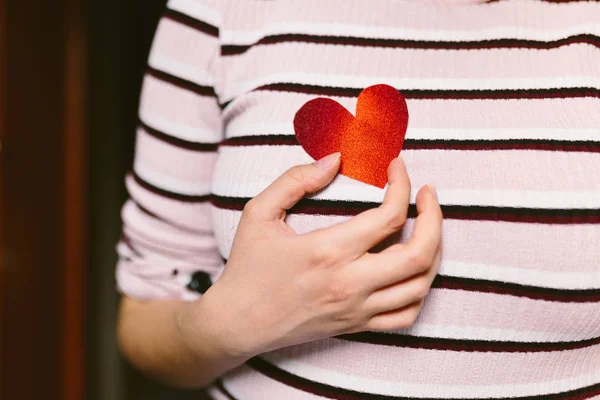 ผู้หญิงสาวที่มีกระดาษแข็งรูปหัวใจแวววาวสีแดงอยู่ใกล้หน้าอก ผู้หญิงที่ถือหัวใจกระดาษแข็งสําหรับวันวาเลนไทน์ ความรักและแนวคิดวาเลนไทน์ . — ภาพถ่ายสต็อก