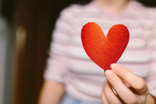 Elinde kırmızı, pırıl pırıl bir kalp olan genç bir kadın. Sevgililer Günü için karton kalp taşıyan bir kız. Aşk ve Sevgililer Günü konsepti. — Stok fotoğraf