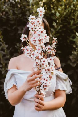 Unrecognizable woman hand holding a branch of almond blossoms. Amazing beginning of spring. Selective focus. Femininity, feminist and feminine concept.