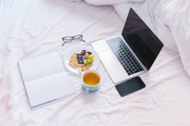 Düz yatıyordu. Evde yatağında çay, laptopunu kontrol etmek, kitap okumak ve kahvaltı yapmak. Üst görünüm