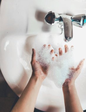 Kadın Covid-19 enfeksiyonunu önlemek için ellerini banyoda yıkıyor. Koronavirüs salgını sırasında sabun ve akan suyla yıkanmayı öneriyor. Üst görünüm