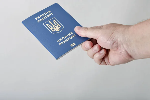 Mano sosteniendo pasaporte biométrico ucraniano contra fondo blanco — Foto de Stock