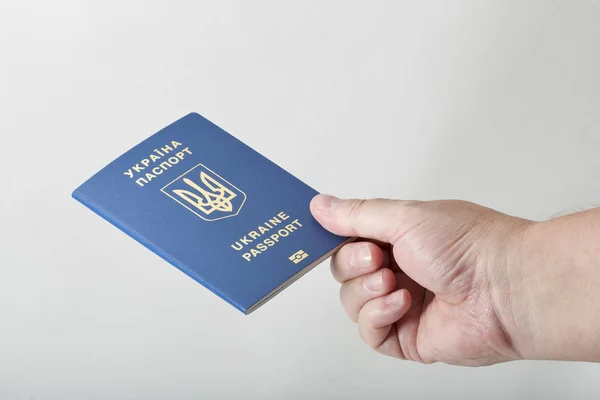 Руки, що тримає біометричний паспорт громадянина України на білому тлі — стокове фото