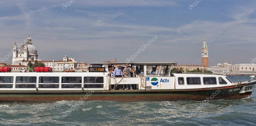 VENICE, ITALY - SEPTEMBER 23, 2016: Water bus or Vaporetto with passengers mooring to Guidecca island in Venice lagoon. Venice is situated across 117 islands separated by canals and linked by bridges.