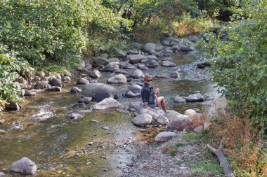 Sonbaharda dağ nehir kaya üzerinde oturan kadın