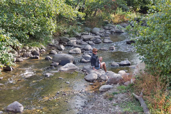Sonbaharda dağ nehir kaya üzerinde oturan kadın
