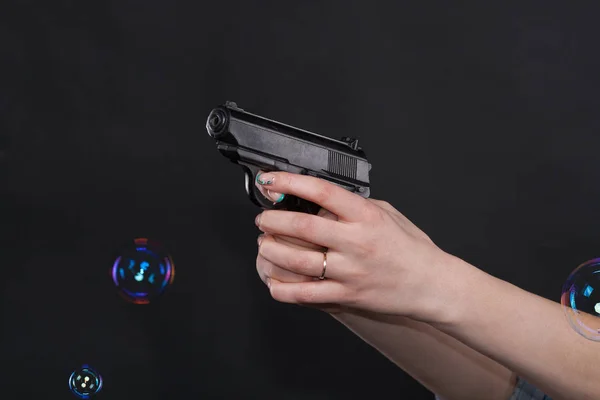 Caucasian women arms holding a gun against black background