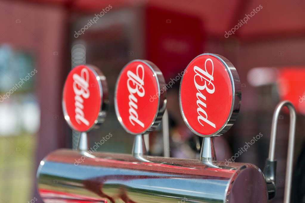 KIEV, UKRAINE - JUNE 28, 2017: Three shining beer faucets with red plates Bud beer closeup. Budweiser is an American style pale lager produced by the multinational corporation Anheuser-Busch InBev.